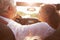 Mature Couple Driving Along Country Road In Open Top Car