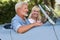 Mature Couple Enjoying Road Trip In Classic Open Top Sports Car Together