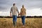 Mature couple holding hands and walking on a cattle farm, bonding and having a stress free day together. Senior farmers