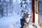 Mature couple, man and woman are sitting on cozy wooden chairs on terrace of country house in winter forest and drinking hot tea,