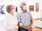 Mature couple in mask protecting against covid examines paintings on display in hall of art museum