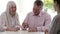 Mature Couple Meeting With Female Financial Advisor And Signing Document