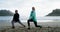 Mature couple performing stretching exercise on beach