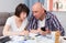 Mature couple with phone calculation money sitting at table