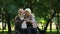 Mature couple resting in park looking at grandkids, man sitting in wheelchair