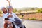 Mature Couple Riding Motor Scooter Along Country Road