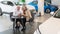 A mature couple is sitting in a car dealership and looking at a smartphone.