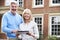 Mature Couple Standing Outside House Looking At Property Details