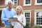 Mature Couple Standing Outside House Looking At Property Details