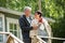 Mature couple standing on porch and drinking hot coffee from mug. They are smiling and laughing, wrapped in a blanket.