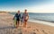 Mature couple surfers with surfboard having fun on empty remote beach enjoying outdoors lifestyle