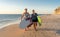 Mature couple surfers with surfboard having fun on empty remote beach enjoying outdoors lifestyle