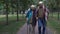 Mature couple with walking sticks walking along elderly home park, support