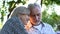 Mature couple watching family album sitting on bench in cozy garden, nostalgia