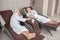 Mature couple in white robes lying on a chaise lounges in a spa center