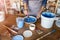 Mature craftswoman painting a plate made of clay in art studio