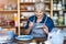 Mature craftswoman painting a plate made of clay in art studio