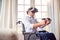 Mature Disabled Man In Wheelchair At Home Wearing Virtual Reality Headset Holding Gaming Controllers