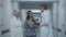 Mature doctor stands in clinic corridor with nurse and patient