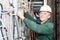 Mature electrician working in hard hat with cables