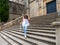 Mature and elegant woman poses on the steps of the cathedral in Baeza, Jaen, Spain with mask and transparent umbrella