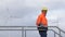 Mature engineer walking in front of wind turbines with protective workwear