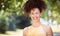 Mature Ethnic Woman Smiling At The Camera. She is outside at the park. Hair in the air