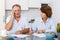 Mature family couple sitting at kitchen table with phone signing documents