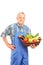 Mature farmer holding a basket full of fresh vegetables