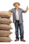 Mature farmer leaning on burlap sacks and giving thumb up