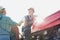 Mature farmer wearing hat and driving tractor while shaking hands with senior farmer