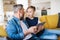 Mature father with small son sitting on sofa indoors, using tablet.