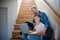 Mature father with small son sitting on the stairs indoors, using laptop.