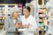 Mature female buyer together with pharmacist scans QR code on medicine label in pharmacy