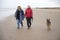 Mature female couple laughing and holding hands walking along the beach