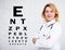 Mature female doctor or nurse posing over white wall with eye test chart