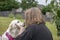 Mature female owner kissing young golden retriver puppy outdoors in garden