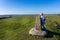 Mature female rambler admiring beautiful hilltop view from a triangulation point or trig point on White Sheet Hill in Wiltshire