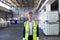 Mature female staff in reflective jacket standing in warehouse