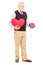 Mature gentleman holding a red heart and gift
