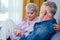 Mature good-looking well dressed couple sitting in sofa in day light from big window and yellow curtains in living room