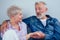 Mature good-looking well dressed couple sitting in sofa in day light from big window and yellow curtains in living room