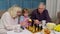 Mature grandmother grandfather with child girl grandchild playing chess game with on table in room