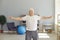 Mature gray haired man doing exercises or light fitness workout at home or rehabilitation clinic