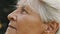 Mature gray haired woman enjoyng autumn breeze in park. Close up