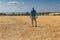 Mature hiker heading for Dnipro river through harvested wheat field