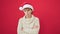 Mature hispanic woman standing upset wearing christmas hat over isolated red background