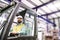 Mature industrial man engineer sitting in a forklift in a factory.