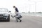 Mature insurance agent analyzing breakdown car while businesswoman standing on road against sky