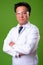 Mature Japanese man doctor wearing protective glasses against green background